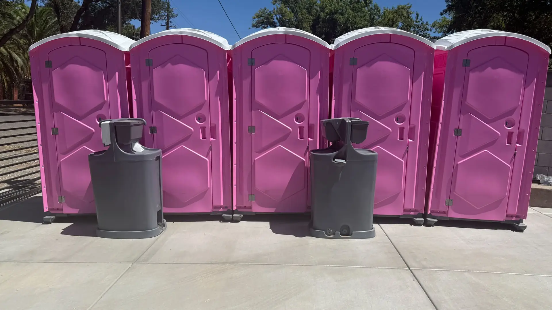Row of pink porta potties with hand-wash stations ready for an event