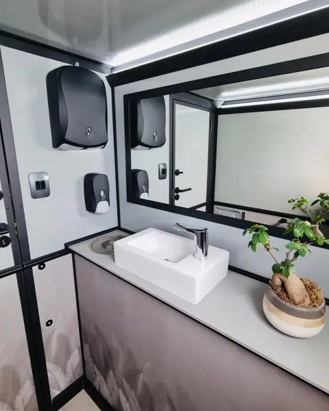 Restroom trailer vanity with sink, mirror and soap dispensers
