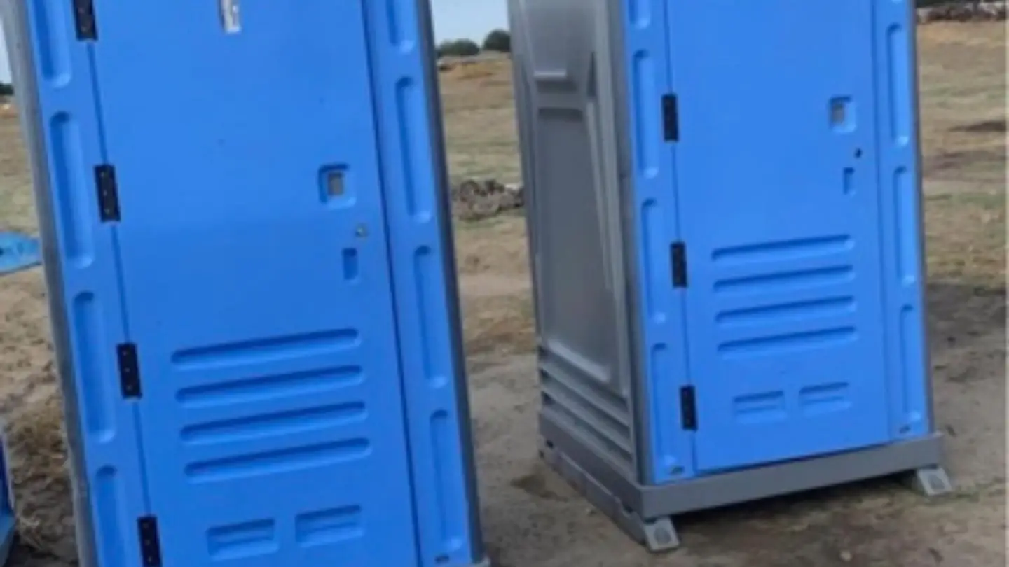 Two porta potties on a dirt construction lot