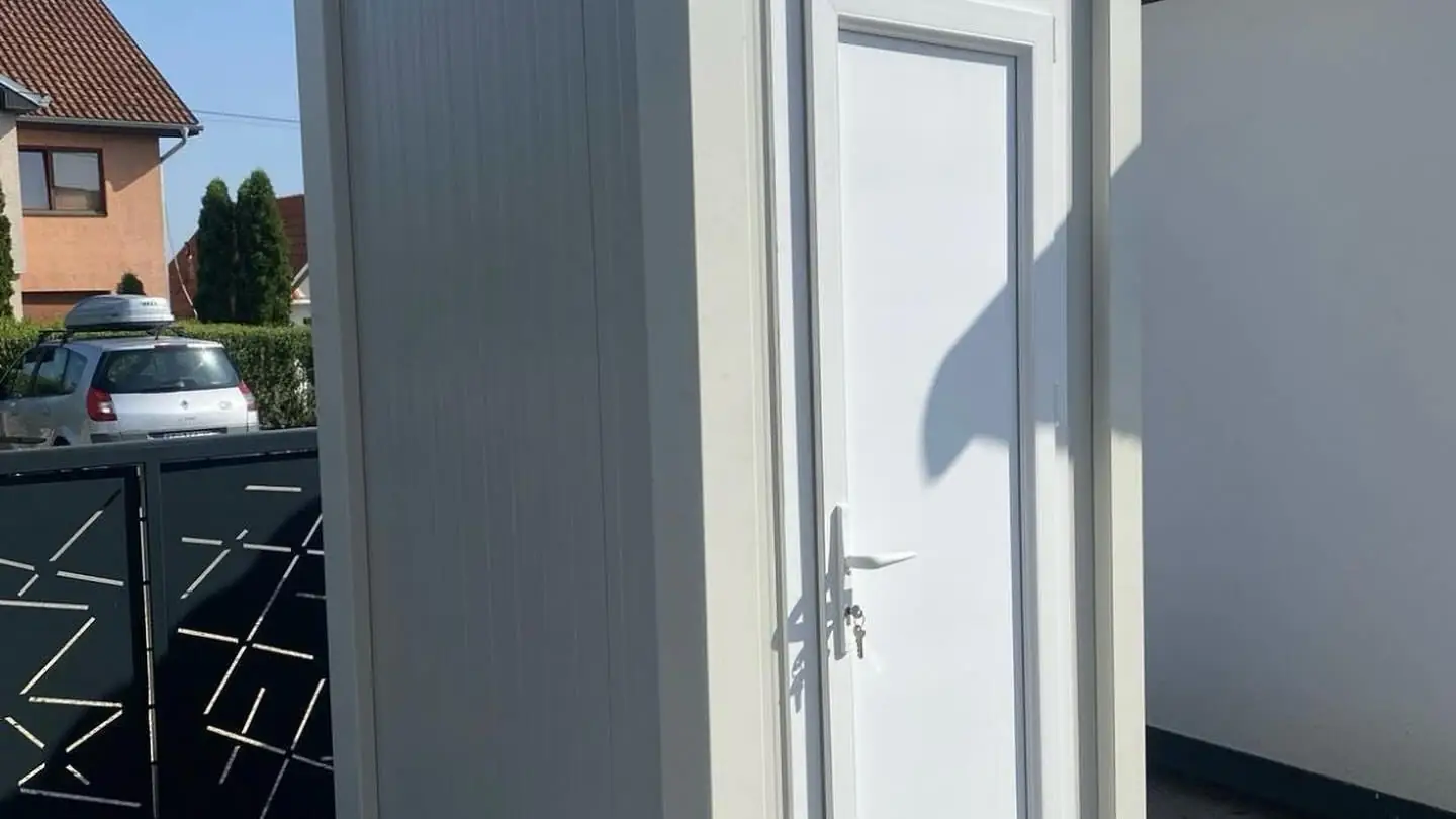 White restroom cabin in a residential driveway